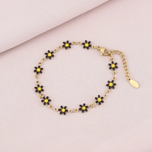 Detailed view of adjustable gold-tone daisy bracelet with black and yellow floral charms