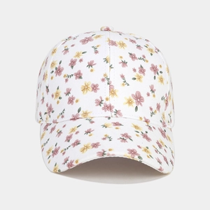 Détail d'une casquette fleurie avec des motifs de fleurs roses et violettes sur tissu blanc
