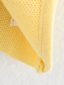 Gros plan sur la texture en maille jaune et les coutures détaillées du tissu