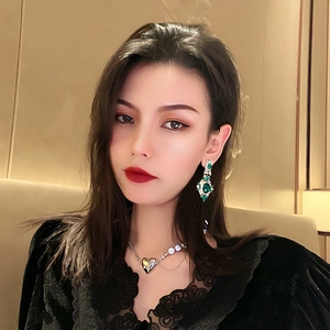 Vintage emerald flower earrings and silver heart necklace worn by a female model