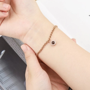 Rose gold projection bracelet with round pendant shown on a female wrist detail