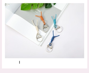 Detailed view of handmade woven rope keychains in orange, blue, and cream with metal hooks