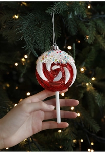 Close-up of red and white lollipop Christmas ornament with sprinkles on a festive tree