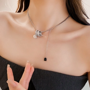 Close-up of a silver zircon paperclip necklace with heart charms and a tassel chain