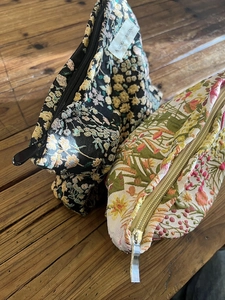 Close-up of floral embroidery textures on canvas makeup bags with metal zippers