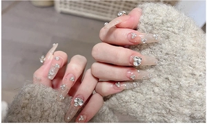 Close-up of long coffin press-on nails with sparkling nude base and luxury heart diamonds