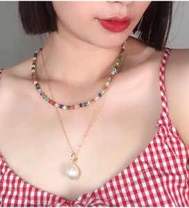 Close-up of double-layer beaded necklace with large pearl pendant and gold chain on model
