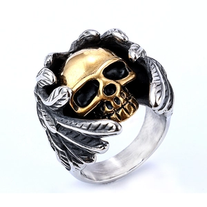 Détail macro d'une bague tête de mort gothique avec visage doré et ailes argentées