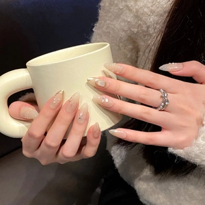 Elegant almond press-on nails with pearls and gold accents on a soft background