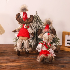 Plush Christmas reindeer dolls wearing festive sweaters on a rustic wooden tabletop