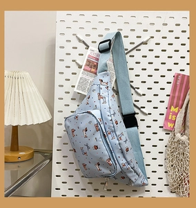 Detail of light blue cartoon dog chest bag with adjustable strap and silver metal zipper