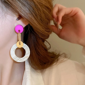 Close-up of asymmetrical marble white resin and pink acrylic geometric drop earring