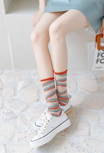 Close-up of sheer striped socks with red rolled edges paired with white sneakers
