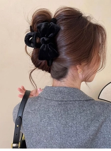 Detail view of large black velvet bow hair claw clip worn in a half-up hairstyle
