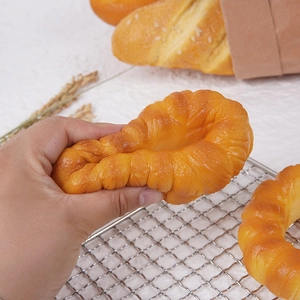 Golden PU slow rebound croissant squishy toy with sesame seeds on metal rack