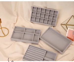 Detailed view of four grey velvet jewelry organizer trays for rings and earrings