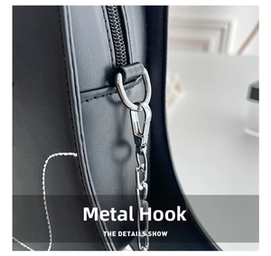 Detail view of silver metal hook and chain on a black leather boot-shaped crossbody bag
