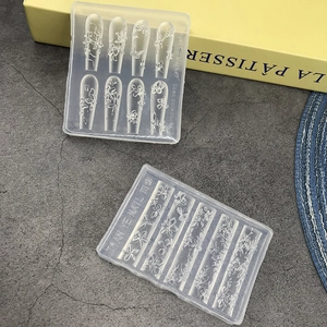 Transparent silicone nail art molds with floral and butterfly patterns on grey desk