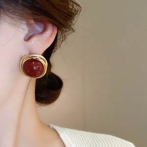 Close-up of vintage burgundy pearl earring with gold spiral metal edge on model