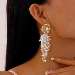 Gros plan de boucles d'oreilles pendantes dorées avec perles et cristaux sur mannequin