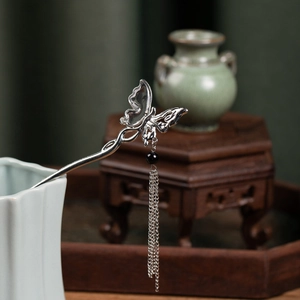 Detailed view of silver butterfly hair stick with long tassel and black bead accent