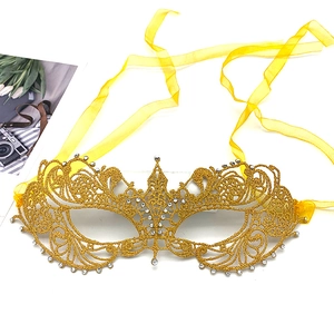Detailed close-up of golden lace masquerade mask with sparkling rhinestones and yellow ribbons