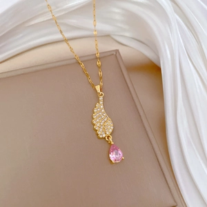 Detail of angel wing pendant with pavé crystals and pink teardrop stone on gold chain