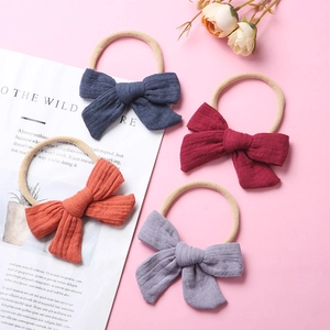 Detail of four colorful muslin cotton baby headbands with elastic nylon bands on pink background
