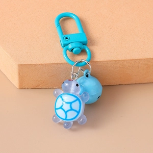 Close-up of a cute blue resin turtle keychain with matching blue bell and metal hook