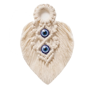 Detailed view of hand-woven beige cotton leaf wall hanging with two blue evil eye beads