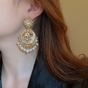 Detail of vintage gold earrings with sparkling crystals and elegant imitation pearls