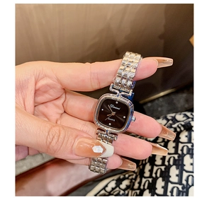 Close-up of a silver square watch with black dial and chain strap on female wrist