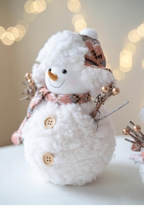 Close-up of plush snowman ornament featuring knitted scarf and carrot nose details