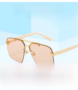 Detail of peach rimless sunglasses with cream temples and gold accents on blue background