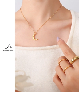 Detail of 18K gold plated stainless steel crescent moon necklace and rings worn on model