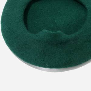 Detailed view of the dark green wool fiber texture on a warm winter beret hat