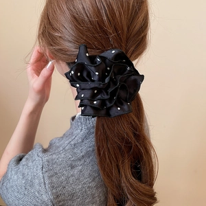 Détail d'un chouchou noir à pois blancs porté sur des cheveux châtains foncés
