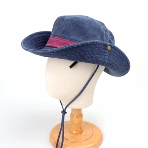Detail of blue denim cowboy hat with burgundy strap and adjustable chin cord on stand