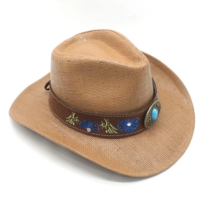 Detail of western straw cowboy hat featuring ethnic embroidery and turquoise medallion