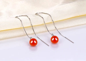 Detail of silver long tassel threader earrings with glossy red agate beads on satin