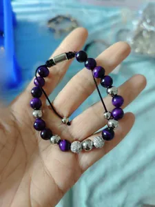 Detail of 8mm purple tiger eye beads and zircon inlaid charms on braided bracelet