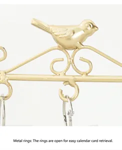 Detail of golden metal bird calendar stand featuring easy-open hanging rings for cards