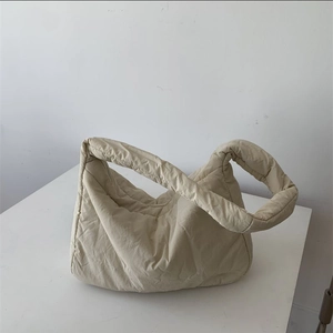 Beige crescent puffer tote bag made of padded nylon with wide strap on white background