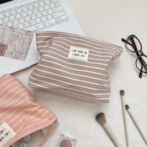 Close-up of striped canvas toiletry bags with colorful embroidered labels and spacious interior