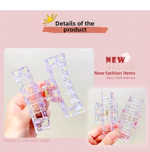 Detail view of transparent acrylic hair claw clip with purple floral prints and gold spring