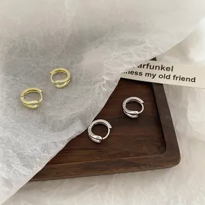 Minimalist gold and silver double-layered twist hoop earrings for women presented on wood