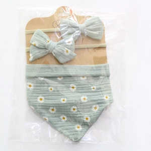 Close-up of baby set with light green floral bib and two matching bow headbands