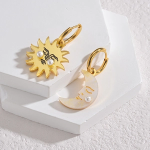 Asymmetric gold sun and moon earrings with pearls on minimalist stone display