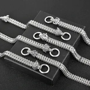 Silver stainless steel men's woven bracelet with wolf and bear head clasps on a gift box