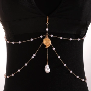 Detail of gold pearl body chain featuring a spiral seashell and irregular drop pearl charm